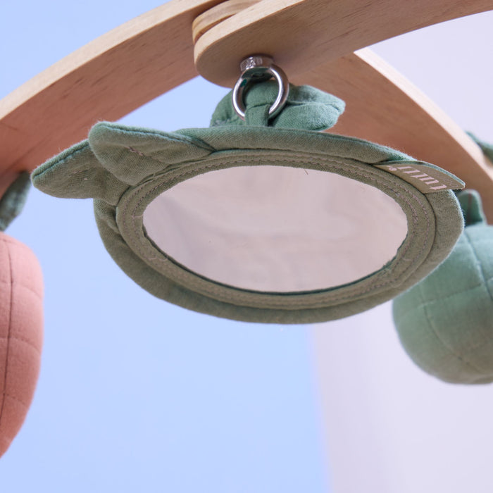 Detailed view of padded leaf-shaped baby-safe mirror suspended from wooden playgym frame.