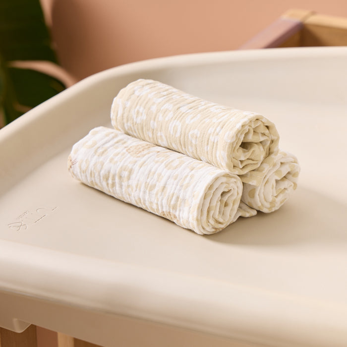 rolled up and stacked Love Cats muslin cloths in mixed leopard prints, shown on a changing unit to showcase soft, lightweight everyday essentials.