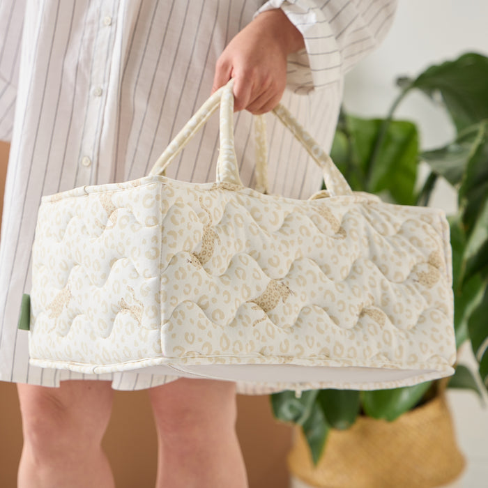 Close-up of parent carrying the Love Cats nappy caddy in beige leopard print, showing quilted finish, soft texture, and sturdy handles
