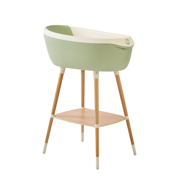 Angle view of the Nati Baby Bath in aloe on a wooden stand, in a white background.