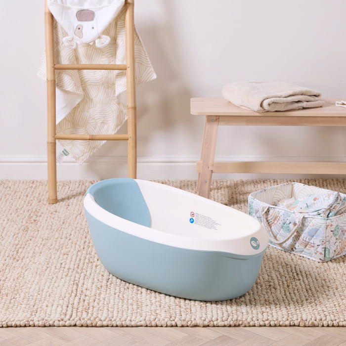 Nati Baby Bath in ocean placed on a textured rug with soft neutral accessories, creating a calm and practical bath space.