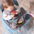 A child eating fruit sitting on the Nova Maison highchair, using the accessory pack, which includes a tray, sippy cup, three nesting bowls, fork, spoon and bib.