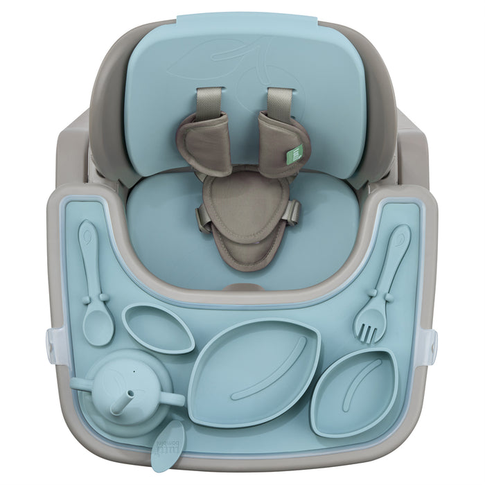Angled top view of Nova highchair in harbour and truffle with silicone mealtime set, styled beside wooden table and rug.