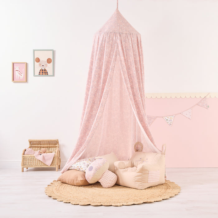 Pink canopy over children's toys in a room with wall decorations.