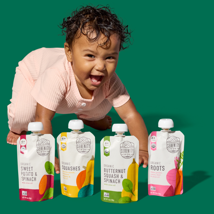 Child playing with Serenity Kids Veggies baby food pouches on a green background