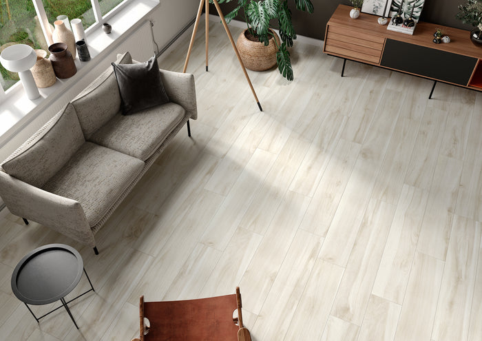 Wood-look porcelain floor tiles installed in a modern living room setting with a gray sofa, wooden sideboard, and plants.