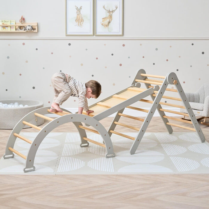 Toddler climbing the Scala Montessori Pikler frame in mushroom finish, building confidence, coordination, and gross motor skills