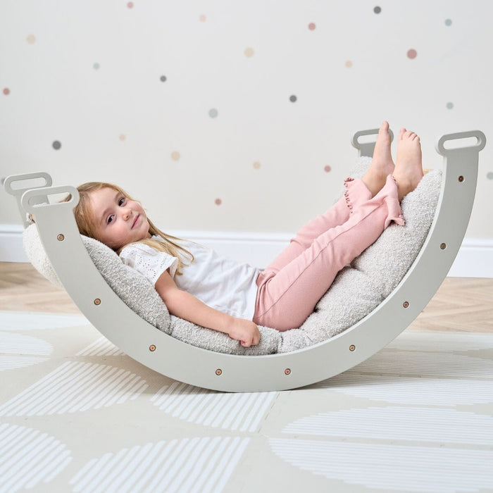 Girl relaxing on the Scala Montessori Pikler Cushion in Boucle Mushroom, highlighting soft texture and ergonomic support for comfort