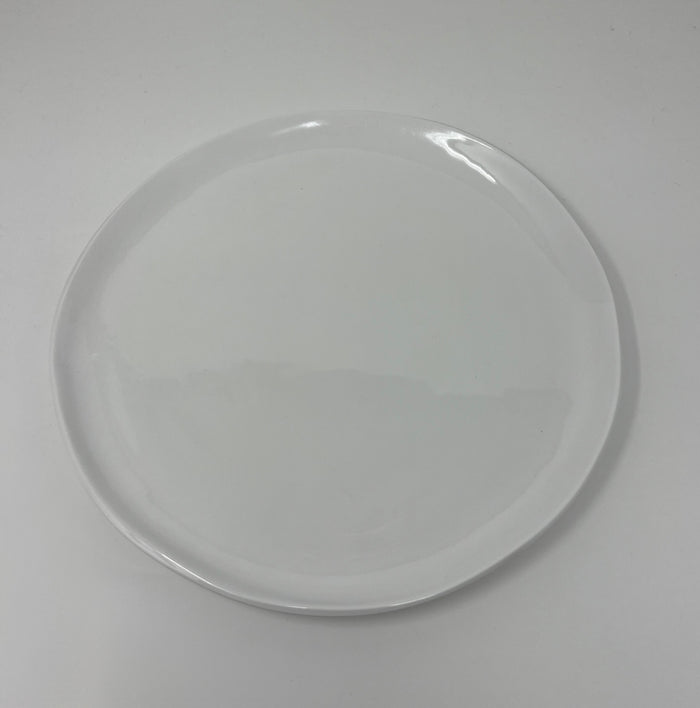 The Relish Simple White Melamine Dinnerware plate, a best seller, features a smooth surface with slightly uneven edges. Centered on a white background, this round plate is dishwasher safe.