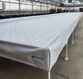 Hydroponic tables with drip caps set up inside a greenhouse for a controlled environment agriculture system, featuring Snap Clamps for Duraskrim Liner by Aquaponics For Life.
