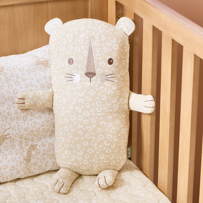 Soft Leopard Cuddle Cushion propped inside a cot bed, showing its gentle animal face embroidery and soft quilted texture