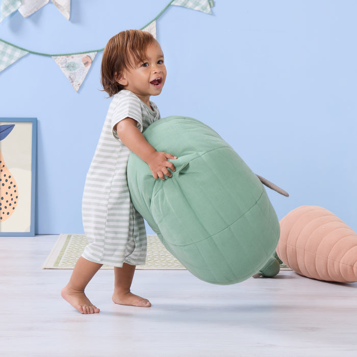 Toddler holding the Soft Muslin Apple Cushion, illustrating its generous size, soft structure and playful, nature-inspired design