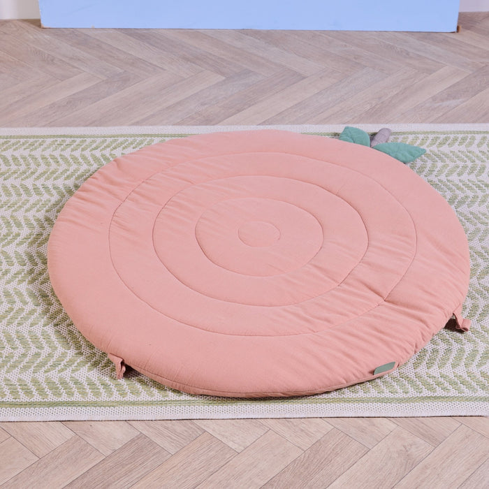 Soft Muslin Padded Playmat in apple shown on woven rug, featuring cushioned circular design and leaf accents.