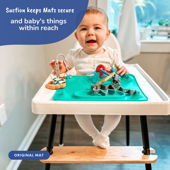 baby sitting in highchair with busy baby suction placemat and toy bungee attached with toys