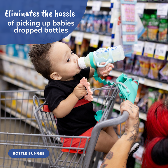 baby in shopping cart with busy baby suction placemat wrapped around handle suctioned to itself with bottle bungee attached and baby drinking from bottle