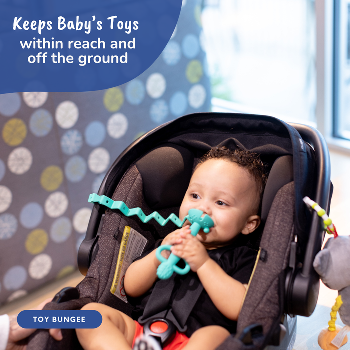 baby in carseat chewing on 2-in-1 teether & Training spoon that is attached to the handle of the seat with toy bungee
