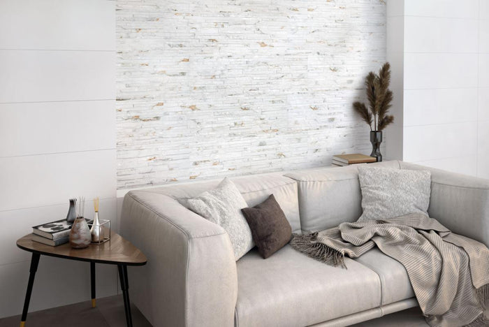 Gray sofa with decorative pillows and blankets in a room with a Thuy Blanco 3D Textured Ledger Look Porcelain Wall Tile