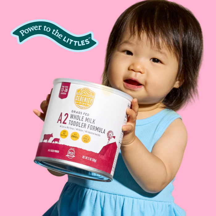 Child holding a container of A2 Whole Milk Toddler Formula against a pink background with 'Power to the Littles' logo.