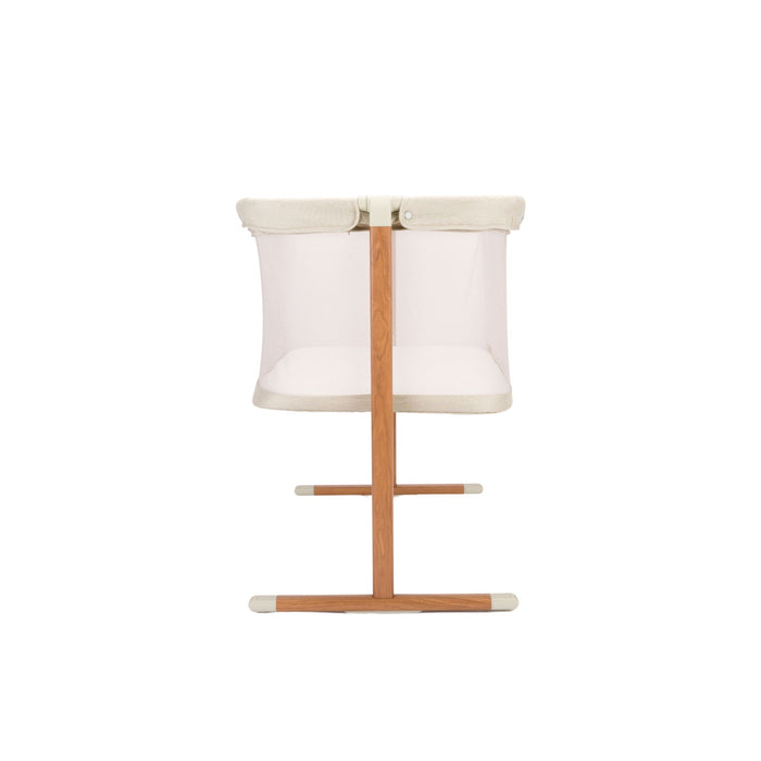Baby crib with ecru top, mesh panel and wooden legs on a white background